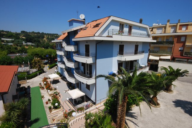 Un edificio blu a più piani circondato da palme.