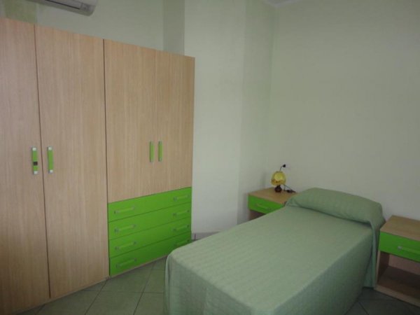 Camera da letto con letto singolo e mobili verdi.