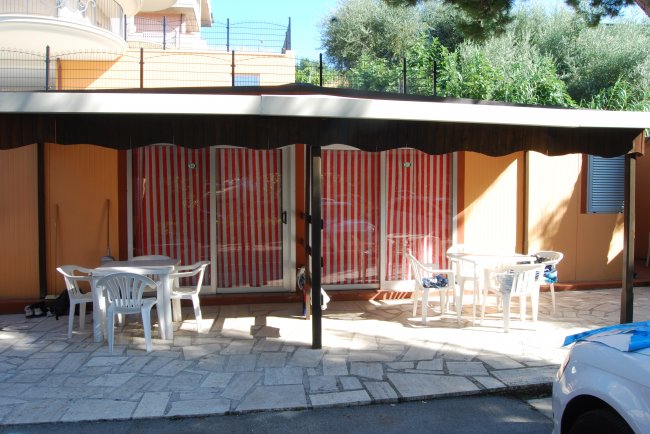 Patio con tavolini rotondi e sedie bianche.