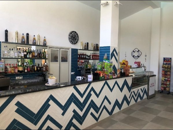 Bancone di un bar moderno con motivo a zigzag blu, bottiglie esposte e snack.