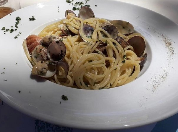 Piatto di spaghetti alle vongole con prezzemolo su un tavolo.
