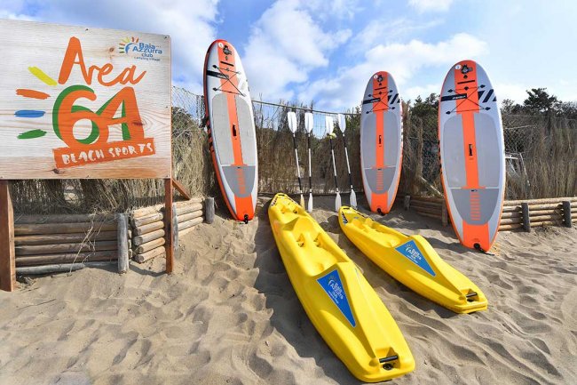 Tavole da surf e kayak sulla sabbia con insegna 
