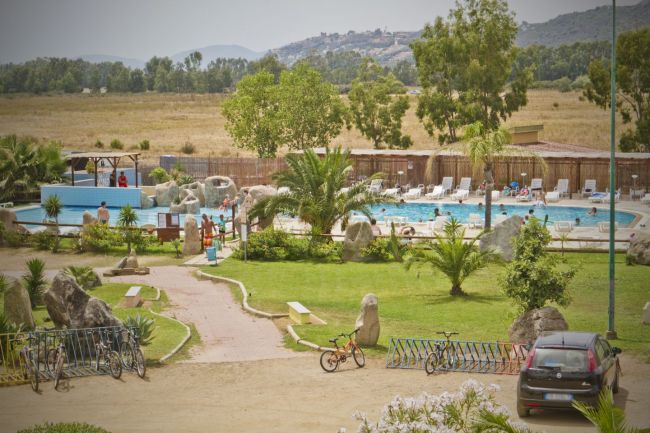 Piscina all'aperto con lettini e palme.
