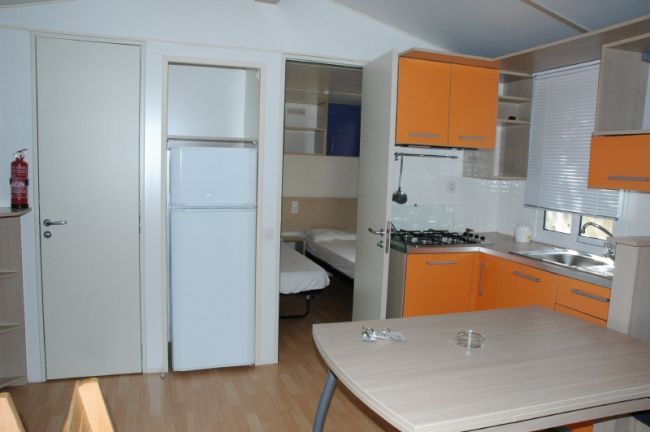 Cucina moderna con armadi arancioni, tavolo di legno, frigorifero e lavello.