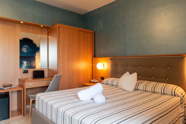 Camera d'albergo accogliente con letto matrimoniale e scrivania.