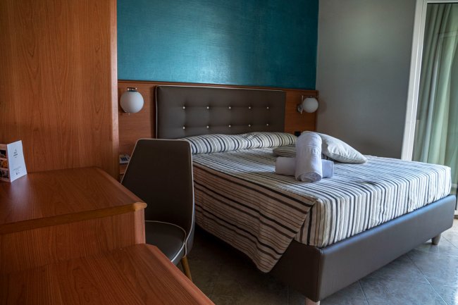 Camera con letto, scrivania e sedia, parete blu.