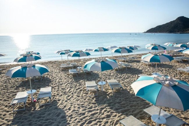 Ombrelloni bianchi e blu su una spiaggia sabbiosa.