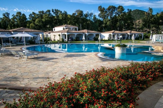 Piscina con villette e fiori rossi sul bordo.