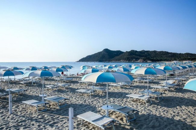 Ombrelloni blu e bianchi su una spiaggia sabbiosa.