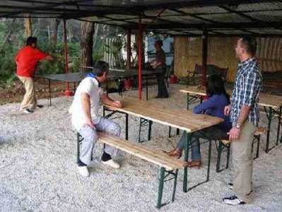 Persone in piedi e sedute su tavoli da picnic in un'area coperta all'aperto.