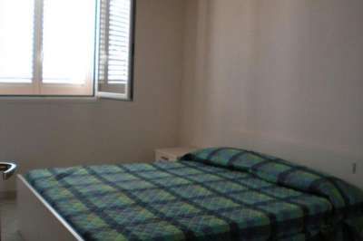 Una camera con letto matrimoniale a quadri blu e verdi, vicino a una finestra con persiane.