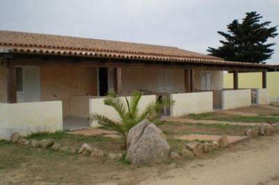 Complesso di villette in stile mediterraneo con portico e giardino curato.