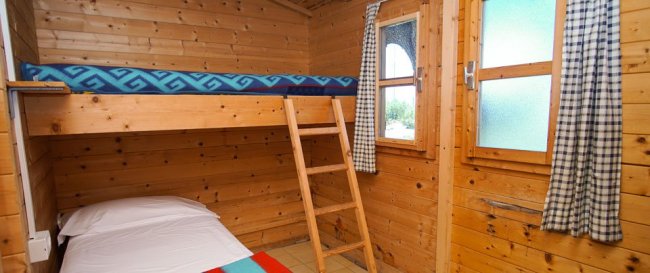 Stanza con letto a castello in legno e finestre con tende a quadretti.