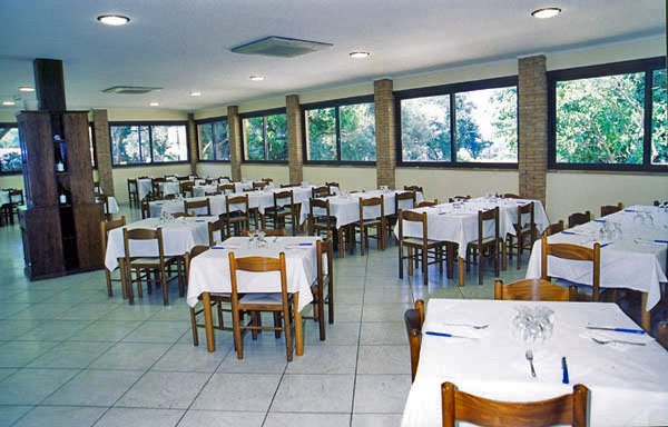Ristorante ampio con tavoli apparecchiati e numerose finestre.