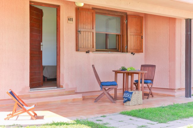 Patio con tavolo e sedie, vicino a una porta e finestra in legno.