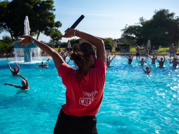 Una persona con una maglietta rossa guida attività in piscina.
