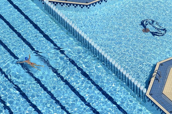 Una piscina con corsie in evidenza, una persona nuota nell'acqua trasparente.