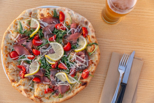 Pizza con fette di limone, pomodori e rucola.