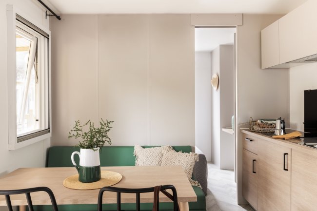 Tavolo da pranzo con sedie nere accanto a un divano verde e cucina.