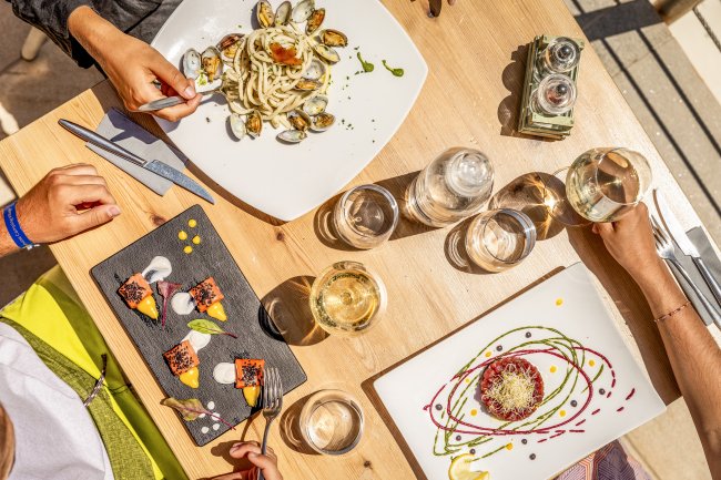 Tavola apparecchiata con piatti creativi, bicchieri di vino e acqua.
