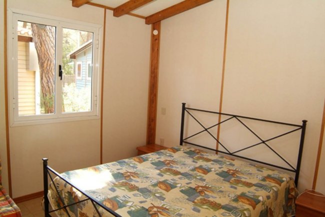 Camera da letto con letto matrimoniale e finestra che affaccia su un giardino.