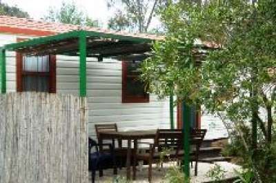 Una terrazza in legno con tavolo e sedie, vicino a un bungalow.