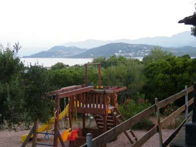 Un parco giochi in legno con vista su montagne e mare sullo sfondo.