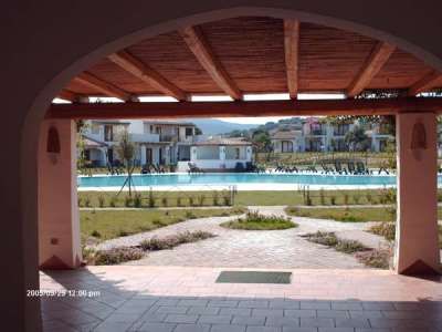 Vista di una piscina incorniciata tra due colonne sotto un portico di legno.