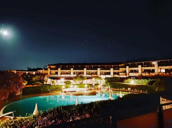 Vista notturna di una piscina e giardino illuminato.
