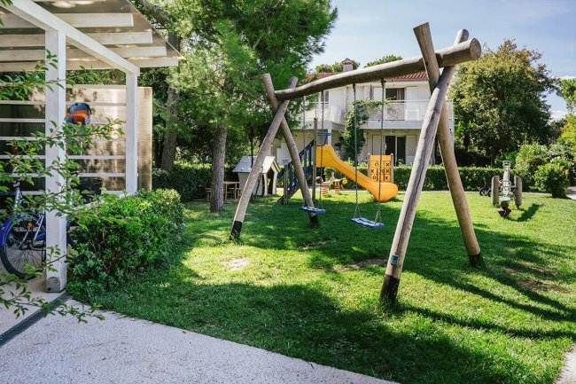 Parco giochi con altalene e scivolo giallo.