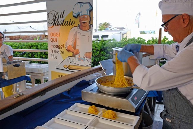 Cuoco prepara pasta in una fiera gastronomica.