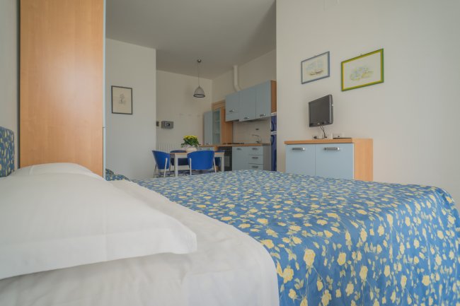 Camera da letto con copriletto floreale blu e mobili chiari.