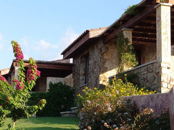 Casa in pietra con fiori e pergolato.