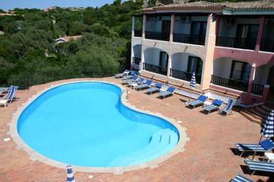 Piscina a forma libera con sedie a sdraio e ombrelloni a strisce.