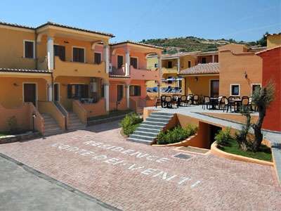 Complesso di edifici colorati con cortile pavimentato e area salotto all'aperto.