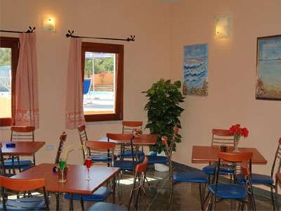 Sala con tavoli, sedie, quadri alle pareti e finestre che danno su una piscina.