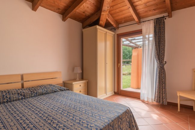 Camera da letto con tetto in legno e porta finestra.