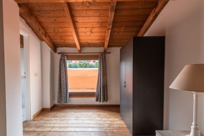 Stanza con soffitto in legno e armadio scuro.