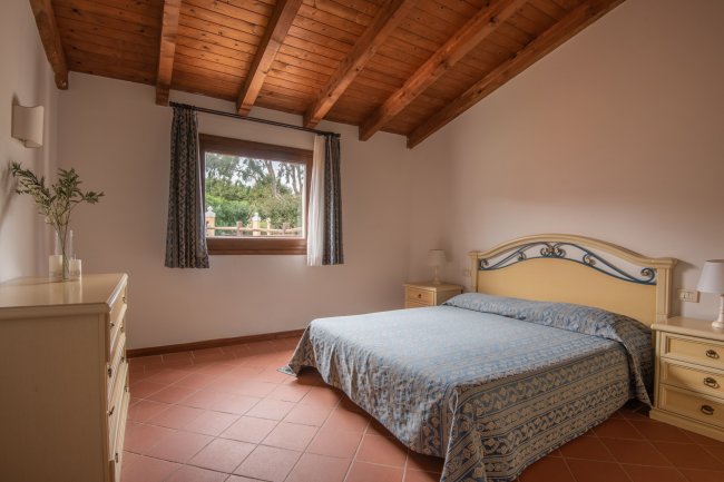 Camera da letto con letto matrimoniale e soffitto in legno.