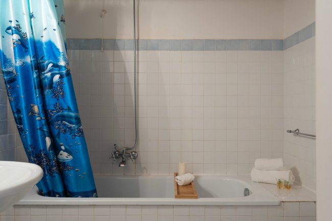 Bagno con vasca e tenda blu.