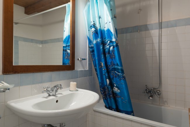 Lavabo accanto ad una vasca con tenda blu.