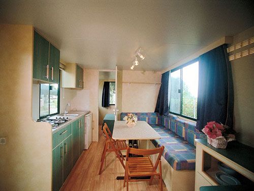 Angolo cucina in una roulotte con tavolo da pranzo, sedie e divano blu.