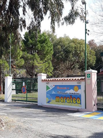 Ingresso del Villaggio Camping Maratea con cancello verde e cartello di benvenuto.