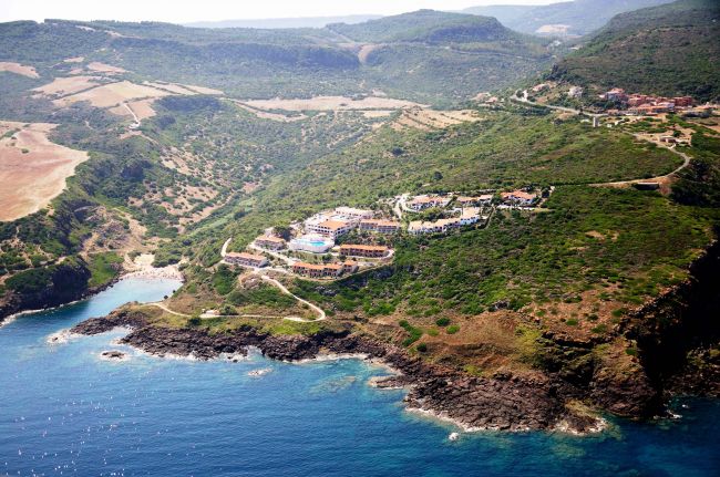 Paesaggio costiero collinare con edifici colorati vicino al mare.