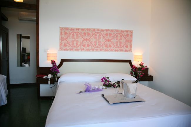 Camera d'albergo con letto matrimoniale, decorazioni floreali e un vassoio.
