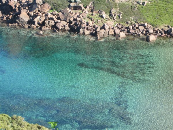 Acqua cristallina con sfumature turchesi circondata da rocce.
