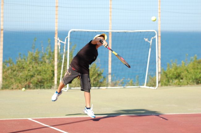 Ragazzo gioca a tennis vicino al mare.