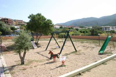 Parco giochi con altalene e scivoli su sabbia.