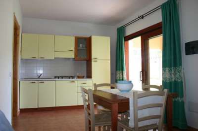 Cucina con mobili gialli e tavolo da pranzo in legno.