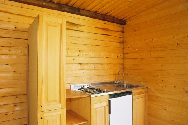 Cucina in legno con lavello, fornelli e un piccolo frigorifero.